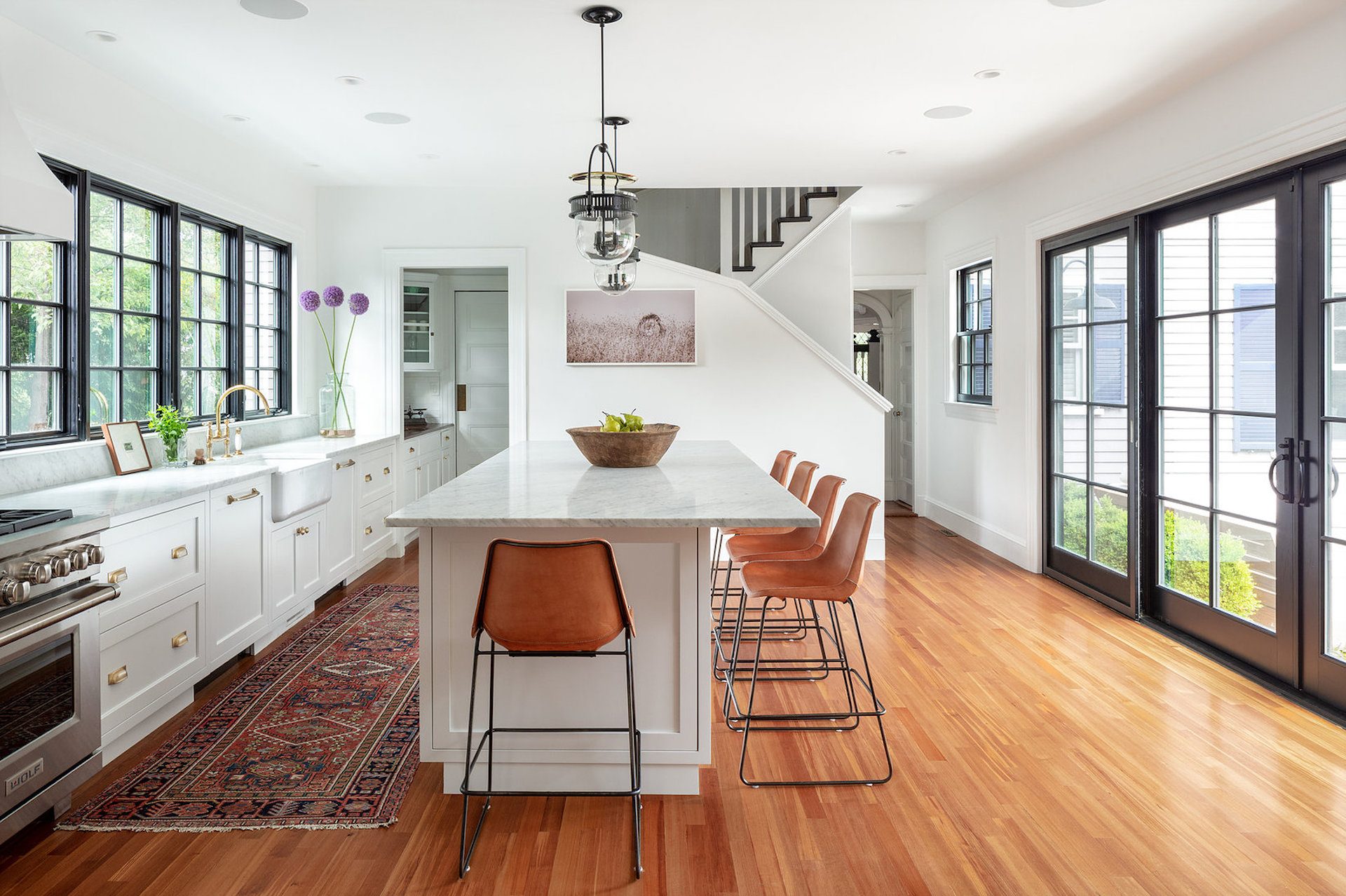 White kitchen with marble island and leather stools