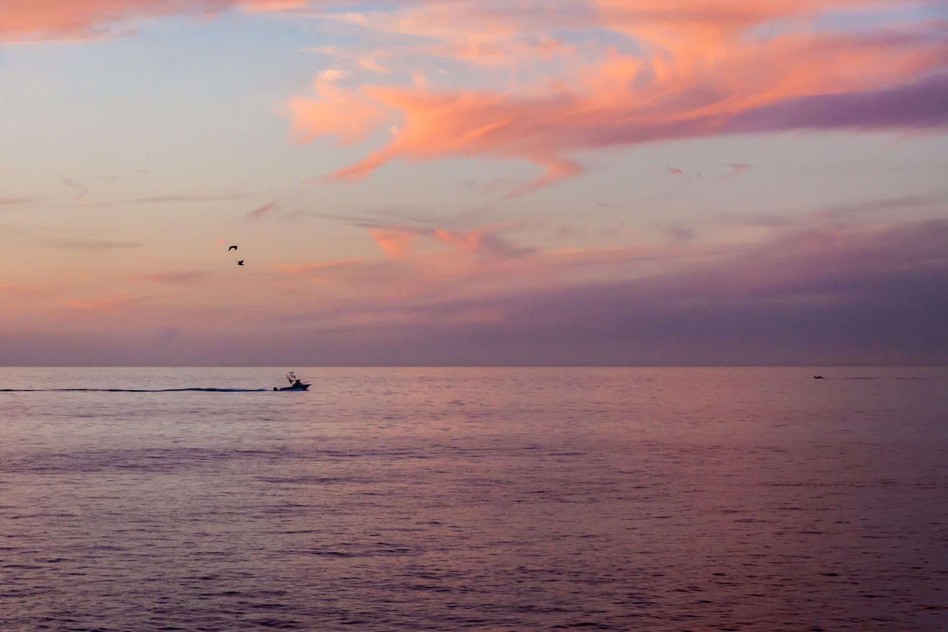 Sailboat on glassy water beneath a pastel dusk sky